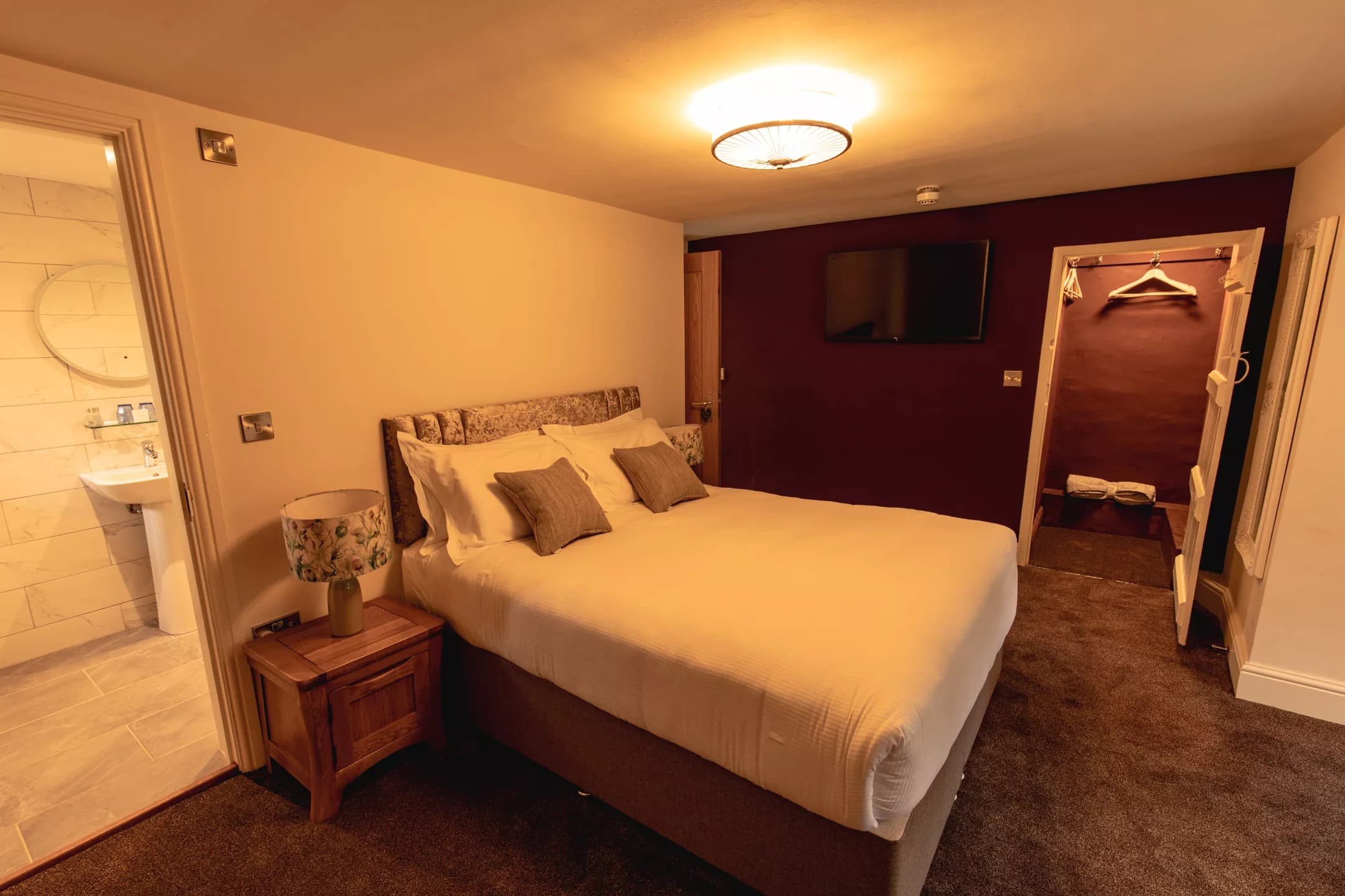 Warm bedroom with burgundy accent wall and Smart TV
